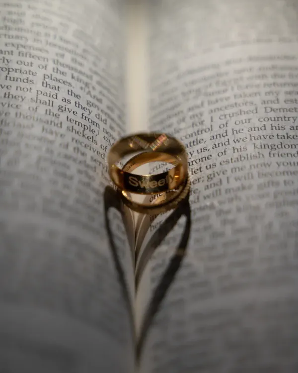 A creative and meaningful shot of the wedding rings. The shadow they cast on the pages of a bible forms a perfect heart, symbolizing a love blessed with faith.