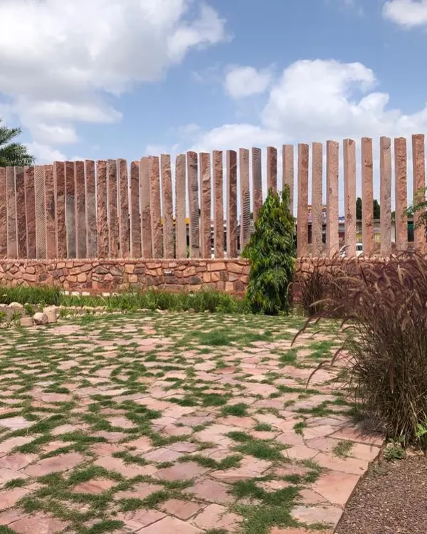 This project in Jodhpur features a boundary created with vertical slabs of local red stone. The design is complemented by a permeable ground cover of stone pavers and native grasses, reflecting the region's natural terrain.