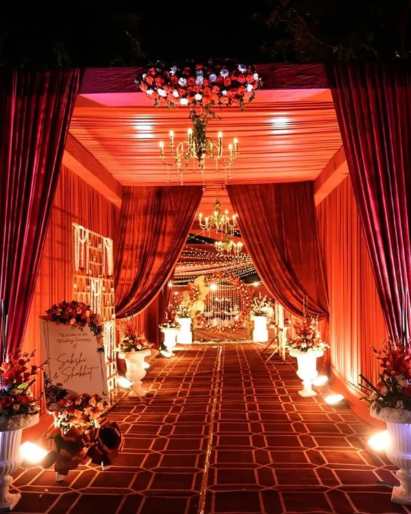 A grand entrance sets the tone for a spectacular wedding. I designed this luxurious entryway with rich red drapes, a crystal chandelier, and floral arrangements, creating a royal welcome for the guests.