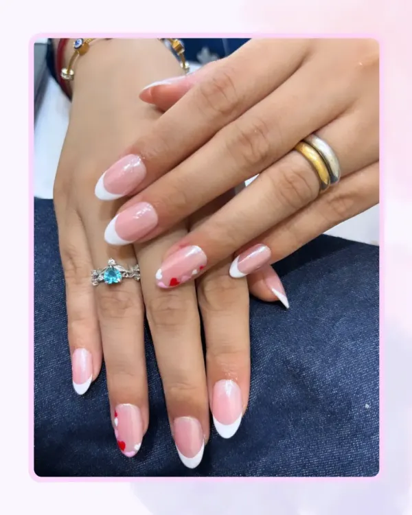 A perfect example of a modern French manicure. The clean, crisp white tips on these almond-shaped nails are complemented by tiny, hand-painted red hearts on the ring fingers.