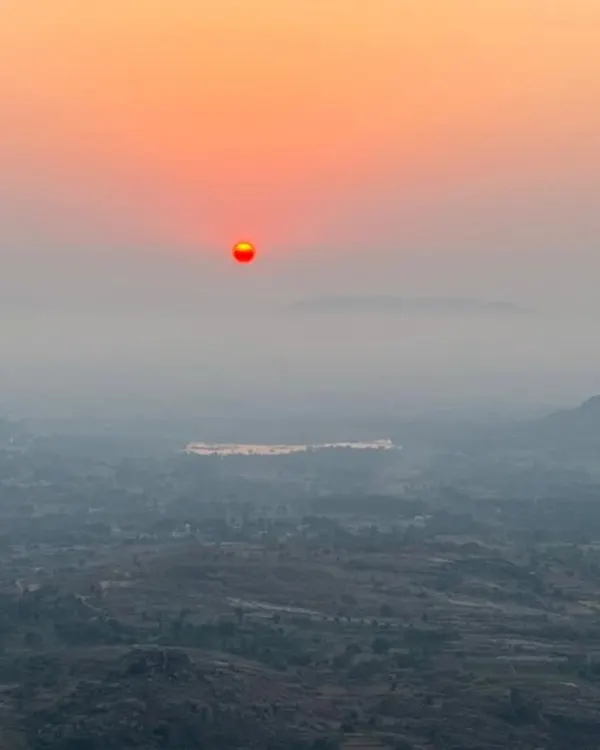The beautiful orange sun rising over a misty landscape, as seen from the top of Minchukallu Betta. This is the view we wake up to.