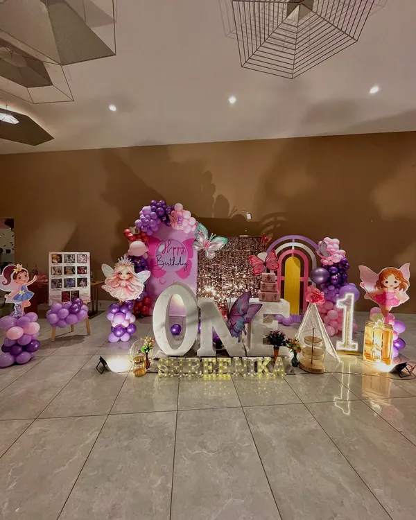 A full view of the enchanted butterfly and fairy theme for Shreenika's first birthday, featuring large 'ONE' letters, a sequin backdrop, and numerous character cutouts.