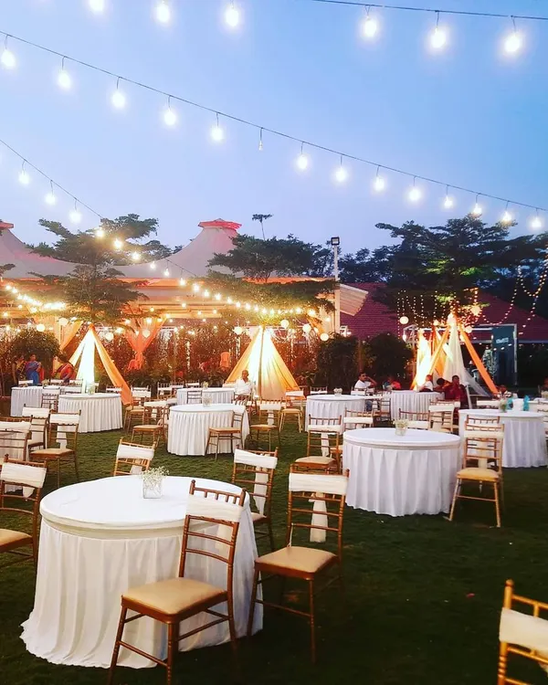 I use lighting to create a magical atmosphere, like this outdoor reception with overhead string lights. The warm, ambient glow makes the entire space feel intimate and celebratory.