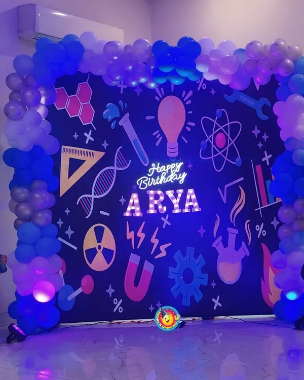 For Arya's birthday, I designed a fun and educational science theme. The backdrop was styled like a chalkboard filled with scientific symbols, framed by a blue balloon arch and featuring cutouts of famous scientists.