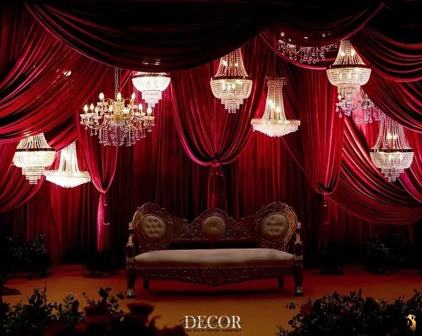 This is the essence of a grand reception. We designed this breathtaking stage with a cascade of crystal chandeliers against a backdrop of rich, red velvet, creating a scene of pure romance and luxury for the happy couple.