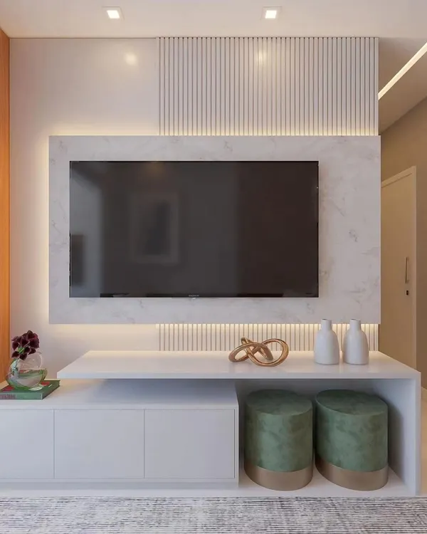 A close-up of a modern, minimalist TV unit. This design features a floating console with both closed cabinets and open shelving, set against a backdrop of white marble and fluted panels with subtle backlighting.