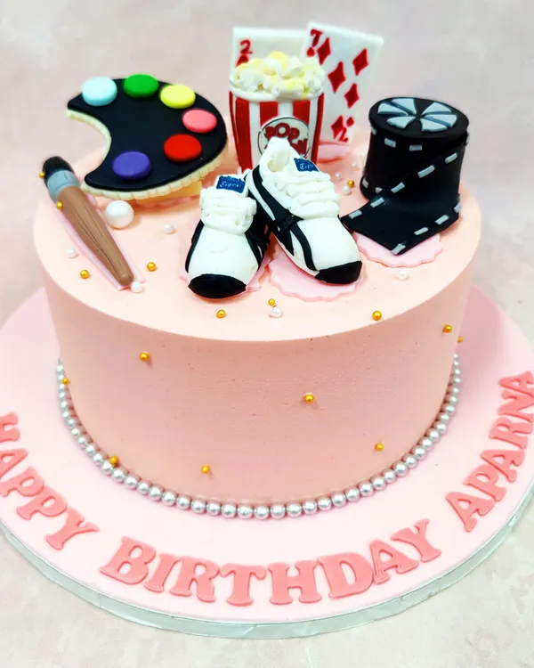 This "Favourite Things" cake is a celebration of hobbies, topped with an artist's palette, popcorn, playing cards, sneakers, and a movie reel.