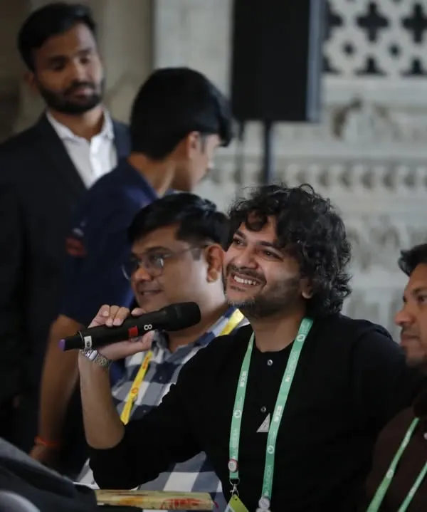 We capture audience participation and Q&A sessions effectively. This photo shows an attendee smiling as he asks a question, highlighting the interactive and engaging nature of the conference.
