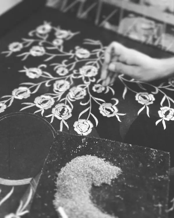 Here is a behind-the-scenes look at one of my skilled artisans at work. This image shows the process of hand-tracing a floral pattern onto fabric before the intricate embroidery begins.