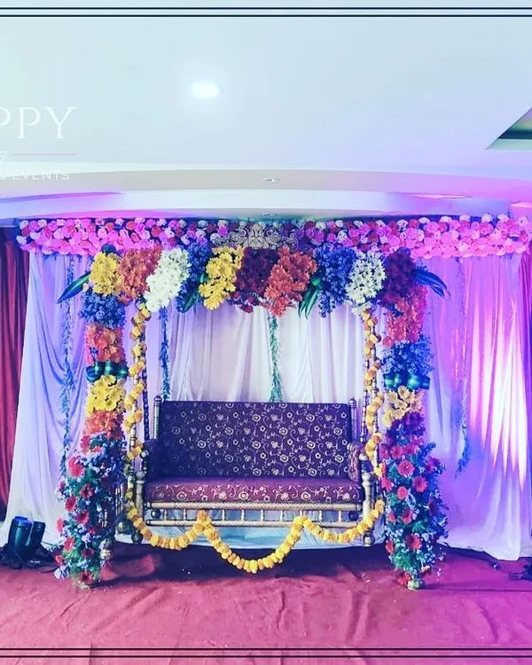 A beautifully decorated swing (jhula) for a baby shower or 'Sreemantham' ceremony. The swing is adorned with multi-colored flowers, creating a joyful and picturesque spot for the mother-to-be.