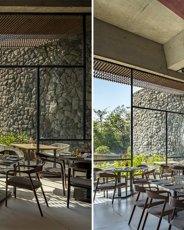 The dining area at the Radisson Resort in Lonavala features floor-to-ceiling windows that look out onto a massive wall of locally sourced stone, blurring the line between interior and exterior.