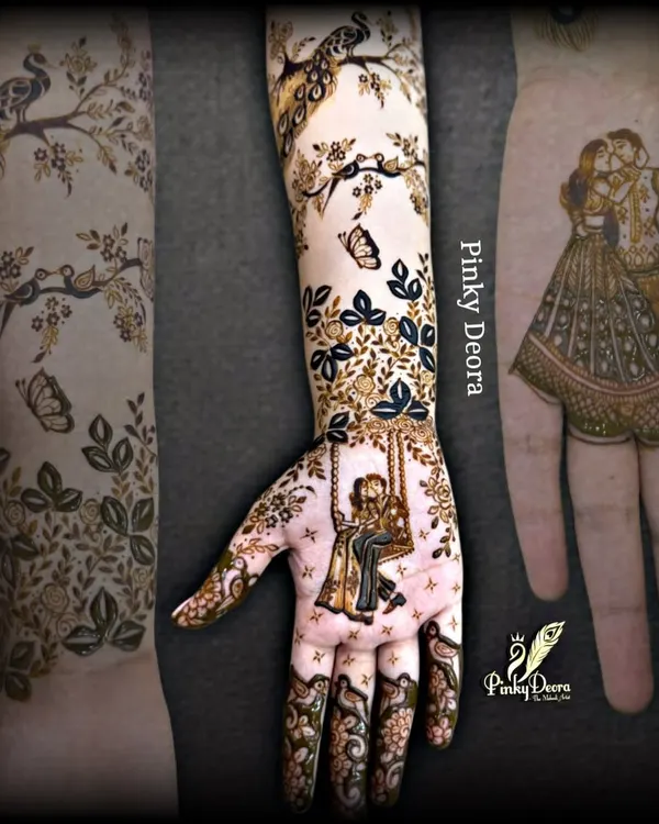 A narrative design showing a couple on a swing on the palm, with the story continuing up the arm with birds and butterflies. This is the art of storytelling in mehndi.