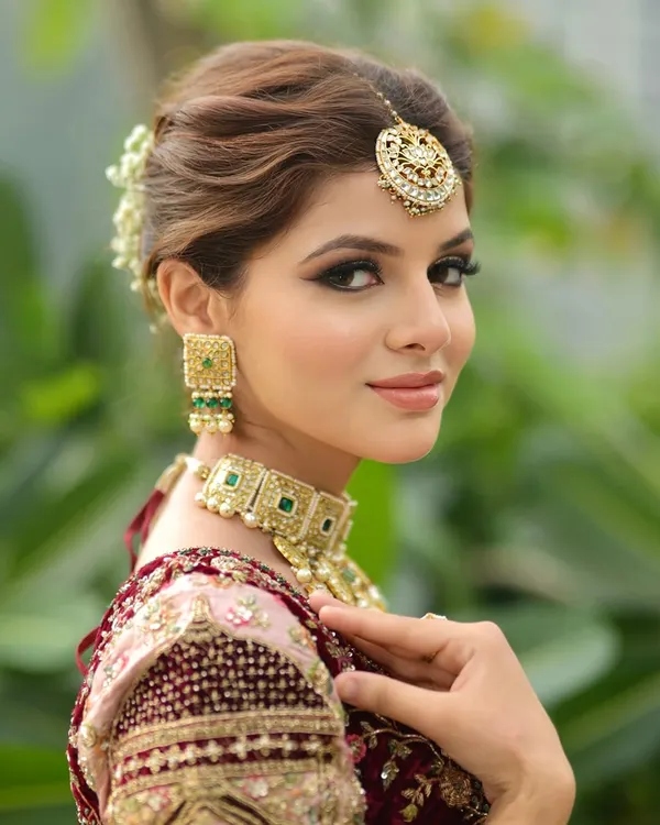 A classic bridal portrait. I created a soft glam look with defined eyes and a neutral lip color to complement her ornate jewelry and pastel lehenga. The hair is styled in an elegant bun adorned with fresh flowers.