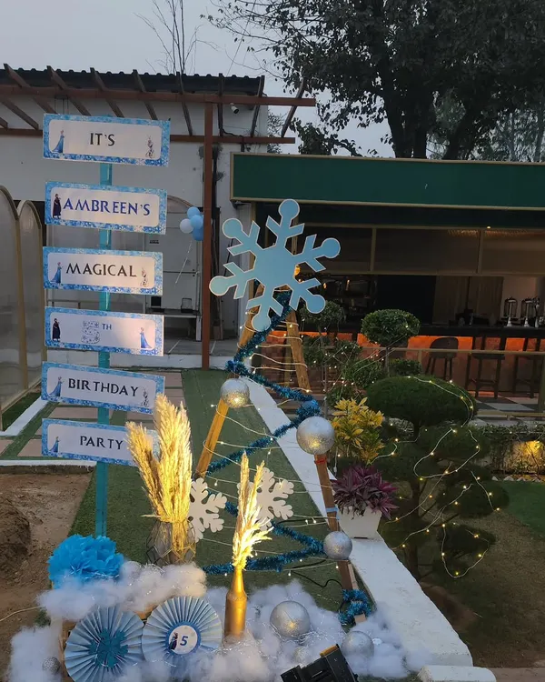 A creative directional sign for a Frozen-themed birthday party. The sign is styled to look like a snowy signpost from Arendelle, guiding guests to "Ambreen's Magical Birthday Party."