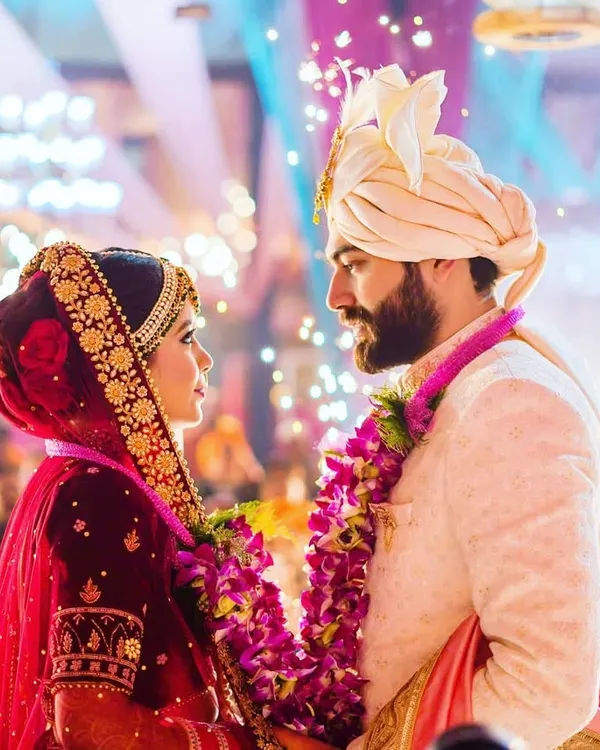 A pivotal moment during the Varmala ceremony, where the couple exchanges garlands under vibrant lights. We focus on capturing the deep connection and shared look between two people as they officially begin their life together.