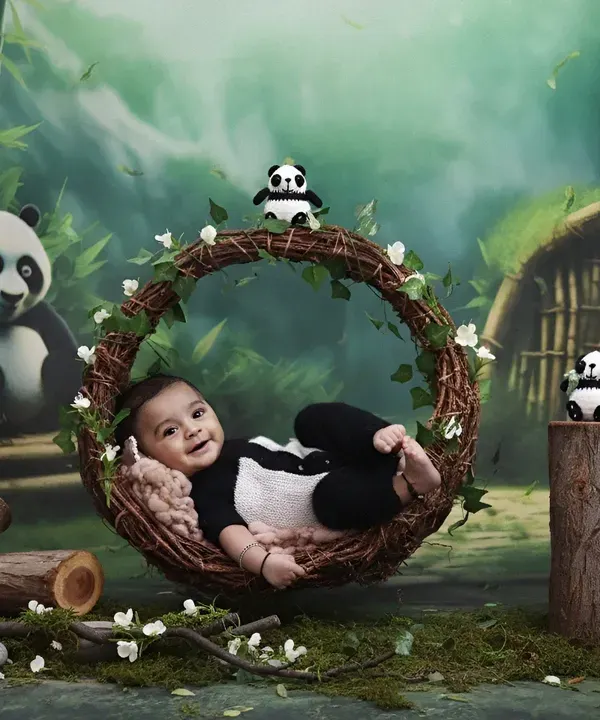 An adorable baby dressed as a panda, smiling while resting in a rustic vine wreath. The lush bamboo forest backdrop completes this charming wildlife scene.