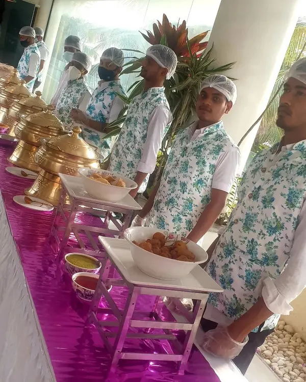 My service staff in their clean, floral-print uniforms, wearing hairnets and gloves as they stand ready at the buffet line. I prioritize hygiene and a professional appearance at every event.