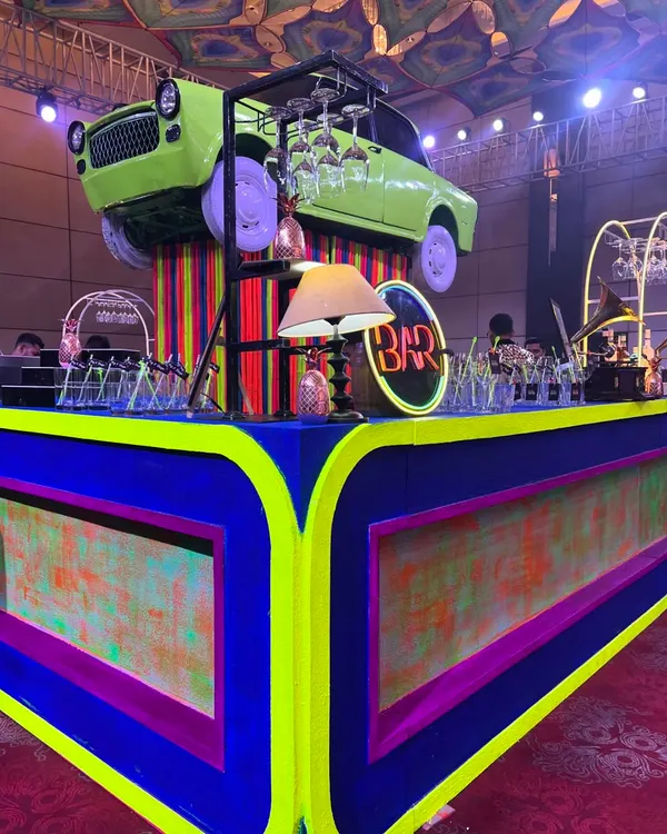 This is what we mean by an immersive experience. For this vintage neon party, we built a custom bar featuring vibrant colors, retro props, and an actual car mounted on top to create a truly unforgettable centerpiece for the sangeet.