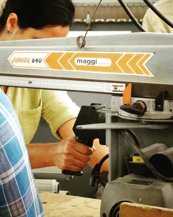 A close-up of a student operating a radial arm saw, highlighting the focus and precision required for machine woodworking.
