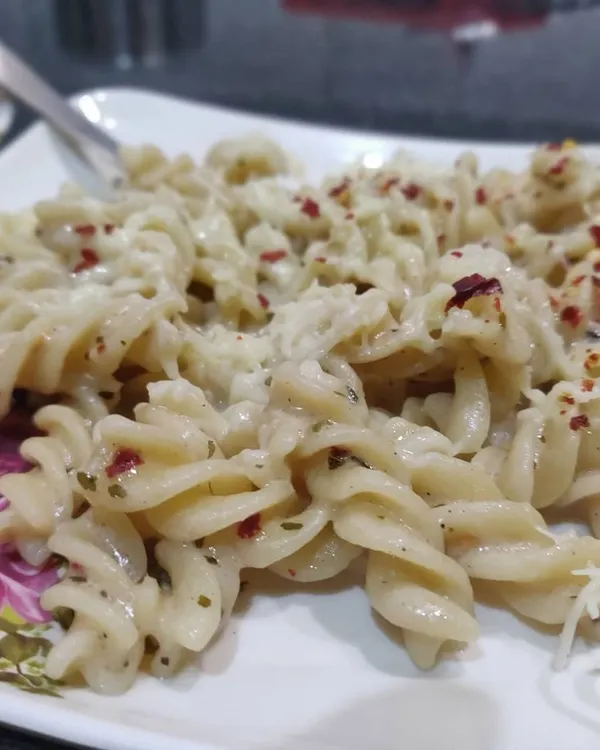 A delicious plate of fusilli pasta in a creamy white sauce, seasoned with herbs and chili flakes. A popular choice for all age groups.