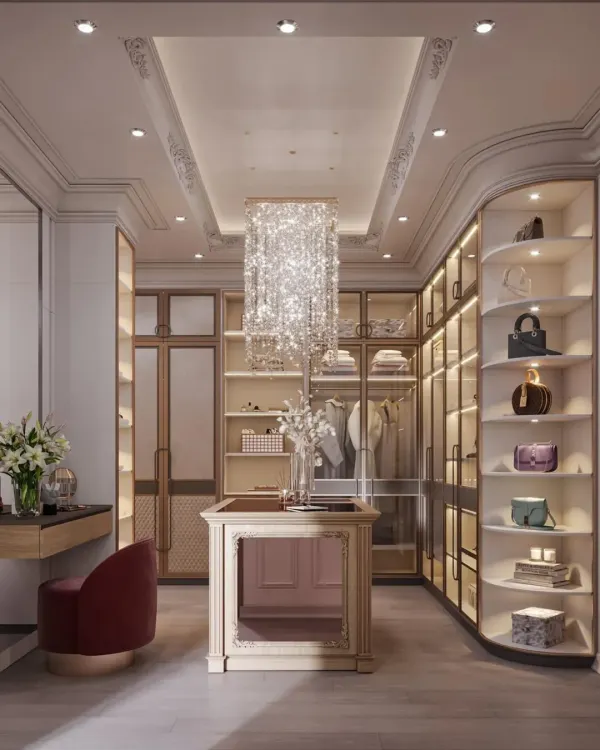 This luxurious walk-in closet features a stunning rectangular crystal chandelier as its centerpiece. The design includes a mix of open shelving for display, glass-door cabinets for protection, and a vanity area with a bold red stool.