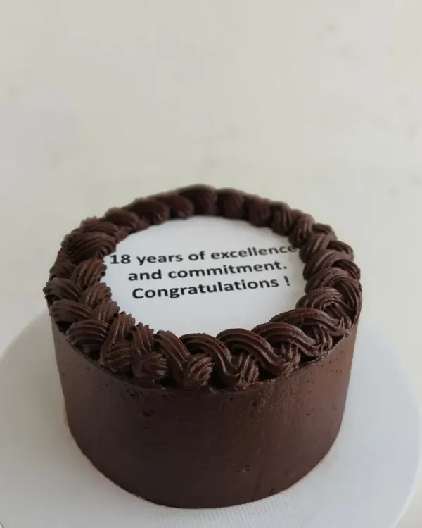 A chocolate bento cake for a corporate milestone, celebrating "18 years of excellence and commitment."