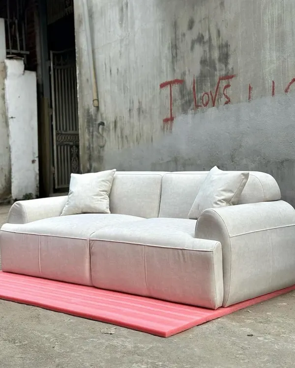A modern, minimalist three-seater sofa with a blocky design and plush, off-white upholstery. This piece is perfect for a contemporary hotel lobby or a minimalist living space.