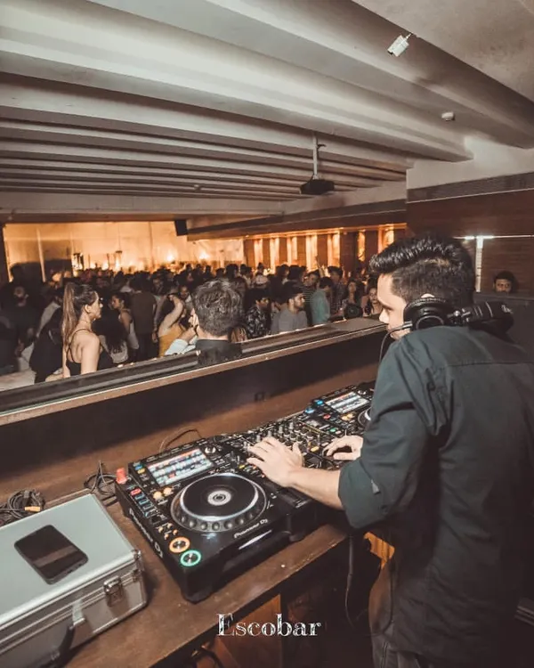 A wide view from behind the console at Escobar, showing a full house ready for a night of desi beats and commercial hits.