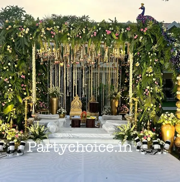 This is our signature peacock-themed mandap for an outdoor wedding. We used a lush floral arch, hanging chandeliers, and two magnificent peacocks crafted entirely from flowers and foliage to create a truly grand and unique wedding stage.