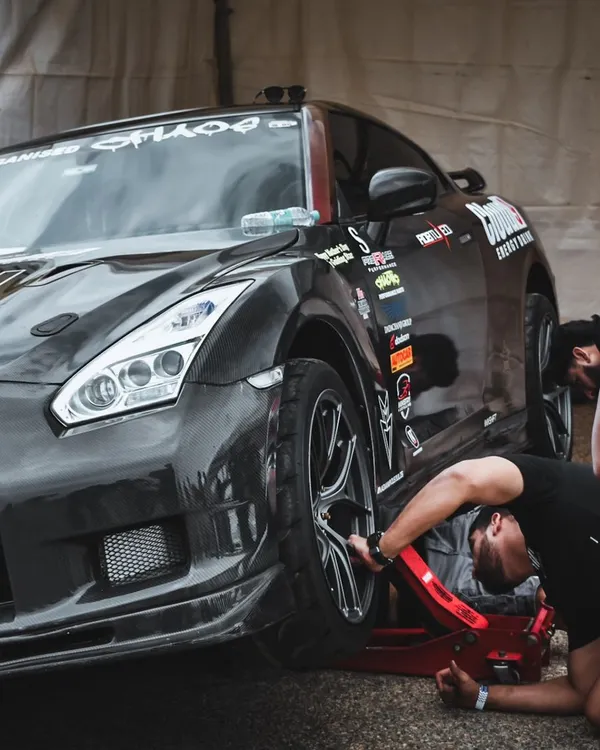 The pit crew at work on a heavily modified Nissan GTR. This is where races are won and lost before they even begin, with meticulous preparation and expert tuning.