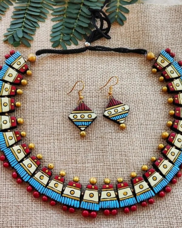 A unique choker-style necklace with geometric textured patterns in maroon, off-white, and sky blue. The matching hook earrings complete this modern, stylish set.