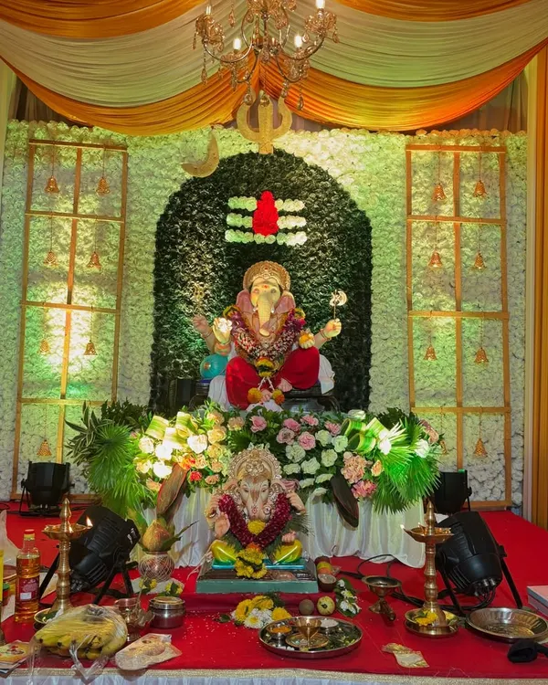 A beautiful Ganpati decoration with a backdrop of white flowers forming a Shivling. I used yellow and white drapes, a hanging chandelier, and spotlights to create a divine setting for the idol.