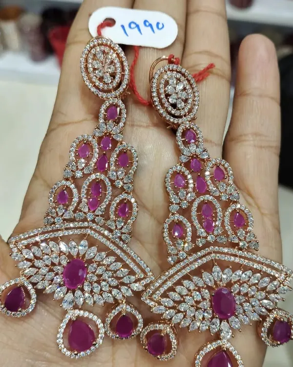 These long, chandelier-style earrings are made with high-quality American diamonds and ruby-colored stones in a rose-gold finish. They are very glamorous and perfect for a cocktail party or reception.