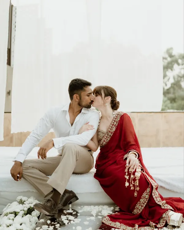 An intimate kiss shared between a couple in a serene, white-draped setting in Jammu. This tender moment captures the romance and stillness at the heart of their story.