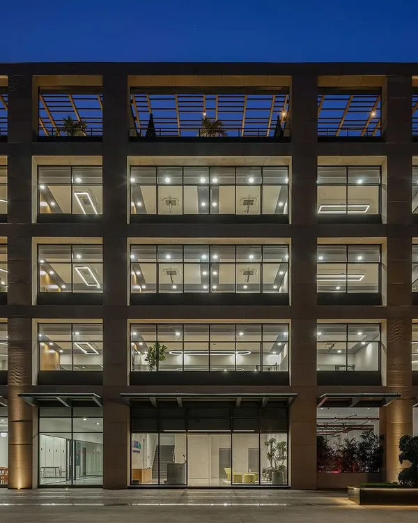 The facade of the Laurus Labs regional office in Vizag at dusk. The grid-like structure and large glass windows showcase the building's open and transparent design, which was engineered for natural cross-ventilation.