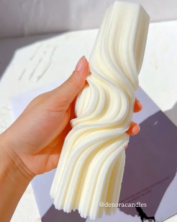 My wave twisted pillar candle, held to show its intricate and fluid design. It's a statement piece of decor, hand-poured from natural soy wax.
