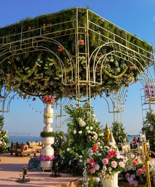 A mandap that feels like a floating garden against the sky. I designed this magnificent structure with a dense canopy of flowers, creating a heavenly space for the couple to exchange their vows by the sea.