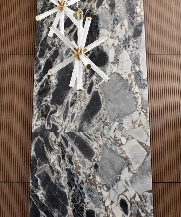 A stunning floor-to-ceiling accent wall that demonstrates our expertise in combining materials. A central slab of dramatic black and grey stone is flanked by warm, vertically fluted wood panels, creating a powerful focal point in this luxury space.