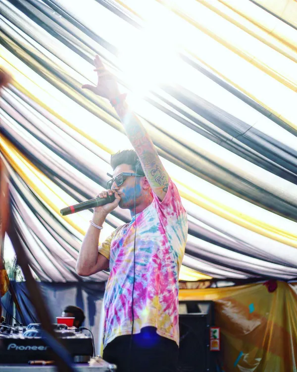 Hyping up the crowd during a daytime Holi party. My tie-dye shirt and the colors on my face show that I get fully into the spirit of the event.