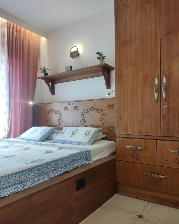 A beautiful master bedroom from the Sampada Home project, where a custom platform bed with a CNC-carved headboard is paired with a matching wardrobe. The design is unified by intricate floral motifs, creating a cohesive and elegant space.