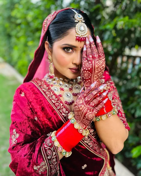 This is the moment it all comes together. The rich velvet of the lehenga, the deep stain of the traditional mehndi, and the perfect bridal glow. I work to make sure every single detail contributes to your final, breathtaking look.
