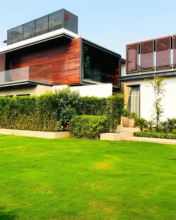 A view of a modern farmhouse in Sultanpur, Delhi. I used a clean, manicured lawn and tall, dense hedges to create a sense of privacy and frame the contemporary architecture of the home.