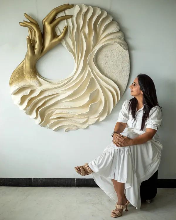 This is me with "The Awakening Cycle," a piece that represents the journey of inner transformation. My art is a form of meditation, and I create each sculpture, like this one made from upcycled paper and mixed media, to be a conversation starter that brings a sense of calm and flow into your space.