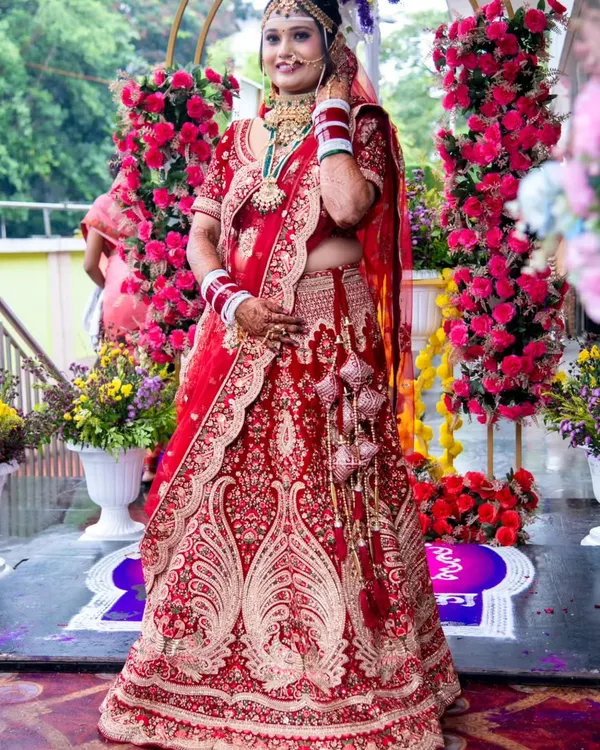 A vision in red. This stunning bride is ready for her forever, dressed in a traditional red lehenga with intricate gold embroidery, perfect for a classic wedding ceremony.