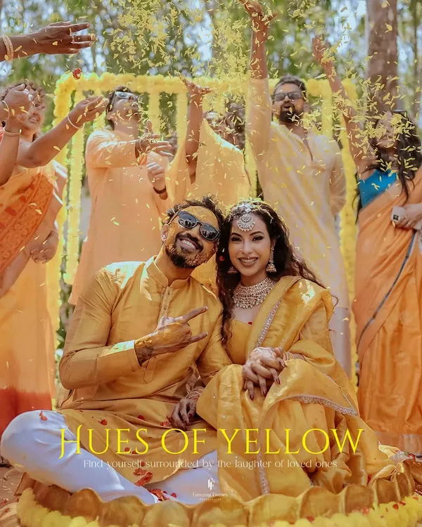A joyful couple, surrounded by friends and family under a shower of yellow petals during their Haldi ceremony. This image, titled "Hues of Yellow," perfectly captures the vibrant energy of the day.
