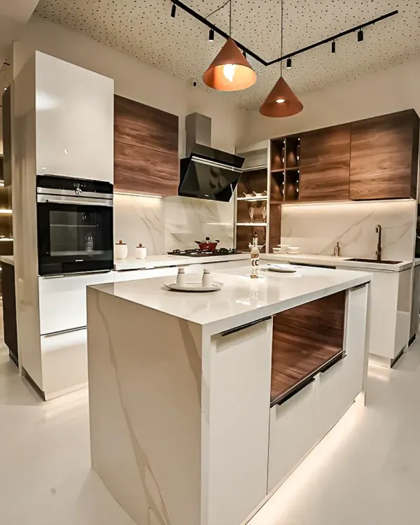 This spacious, modern kitchen features a stunning white quartz waterfall island that doubles as a breakfast counter. The combination of high-gloss white and warm wood-grain cabinets, along with integrated appliances and stylish pendant lighting, creates a luxurious and highly functional space for cooking and socializing.