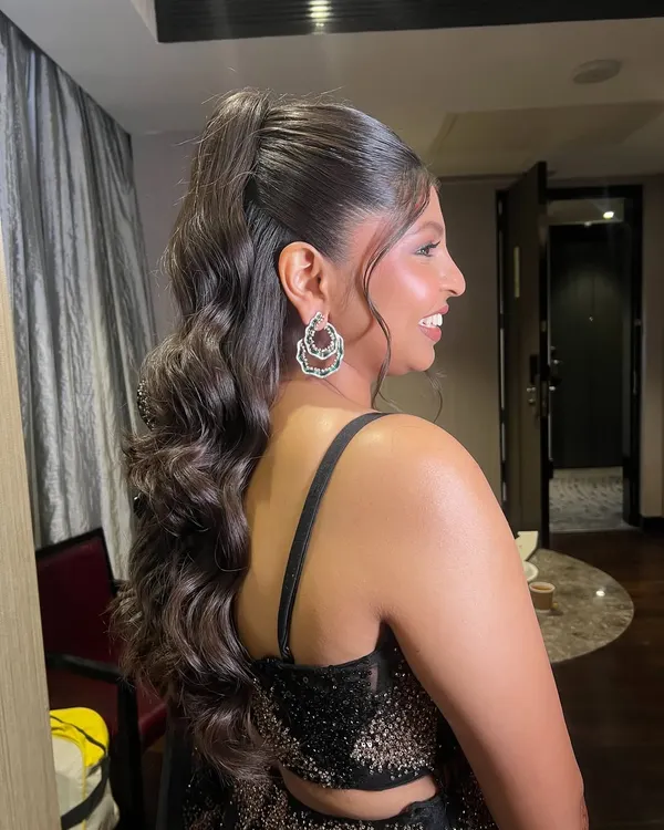 A glamorous high ponytail with beautiful, structured waves. This is a statement hairstyle, perfect for a reception or cocktail event, especially when paired with a modern lehenga.