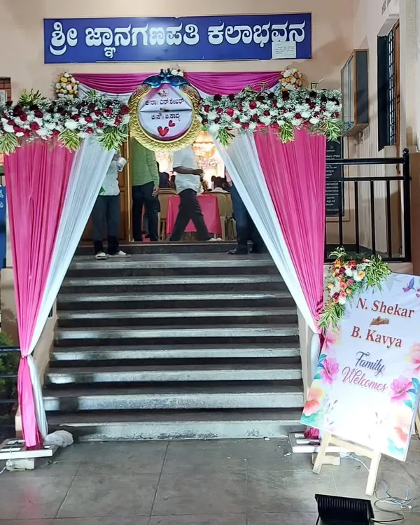 A welcoming entrance we designed for an event at Sri Jnanaganapathi Kalabhavana. The decor includes a floral arch with pink and white drapes and a personalized welcome sign for the couple, N. Shekar and B. Kavya.