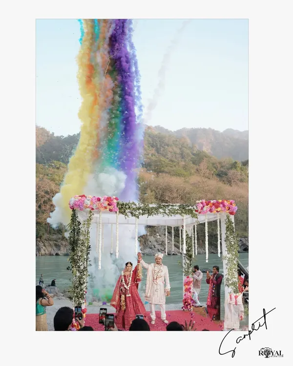 A vibrant Varmala ceremony on the banks of the Ganga, framed by the Rishikesh hills. We specialize in capturing these grand, unforgettable wedding moments.