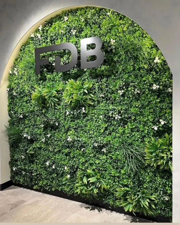 An elegant artificial vertical garden installed in an arched alcove for an office reception area, complete with company branding.